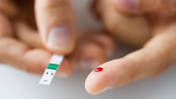 close up of male finger with blood and test stripe
