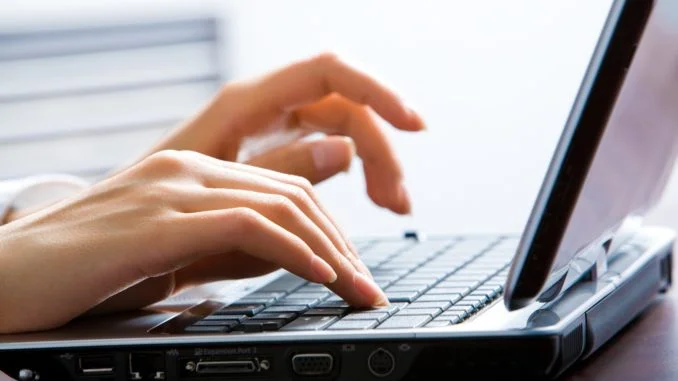 Image of female hands on the keys typing documents