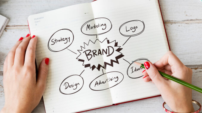 Young woman drawing brand in a notebook creativita impresa progettare